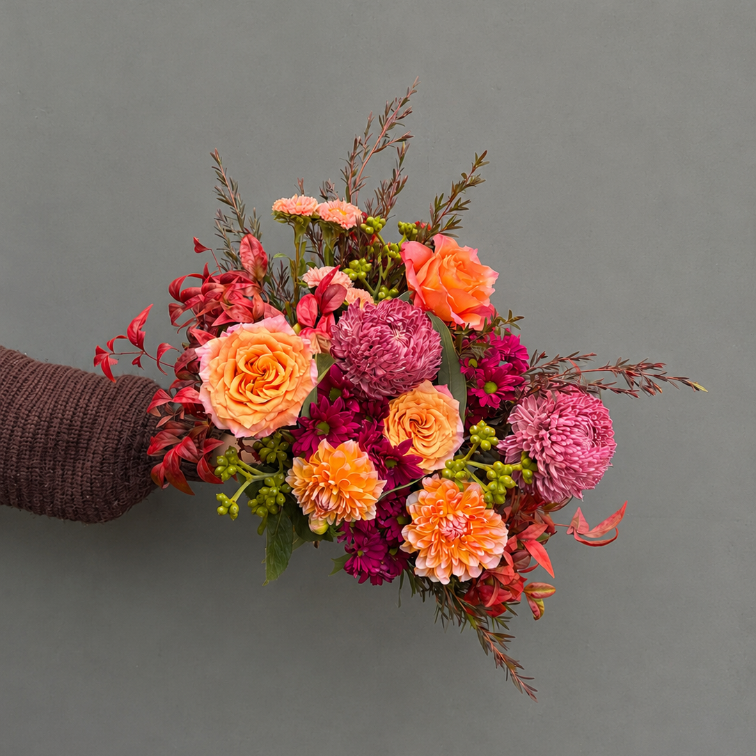 Bouquet of flowers held by a person against a gray background