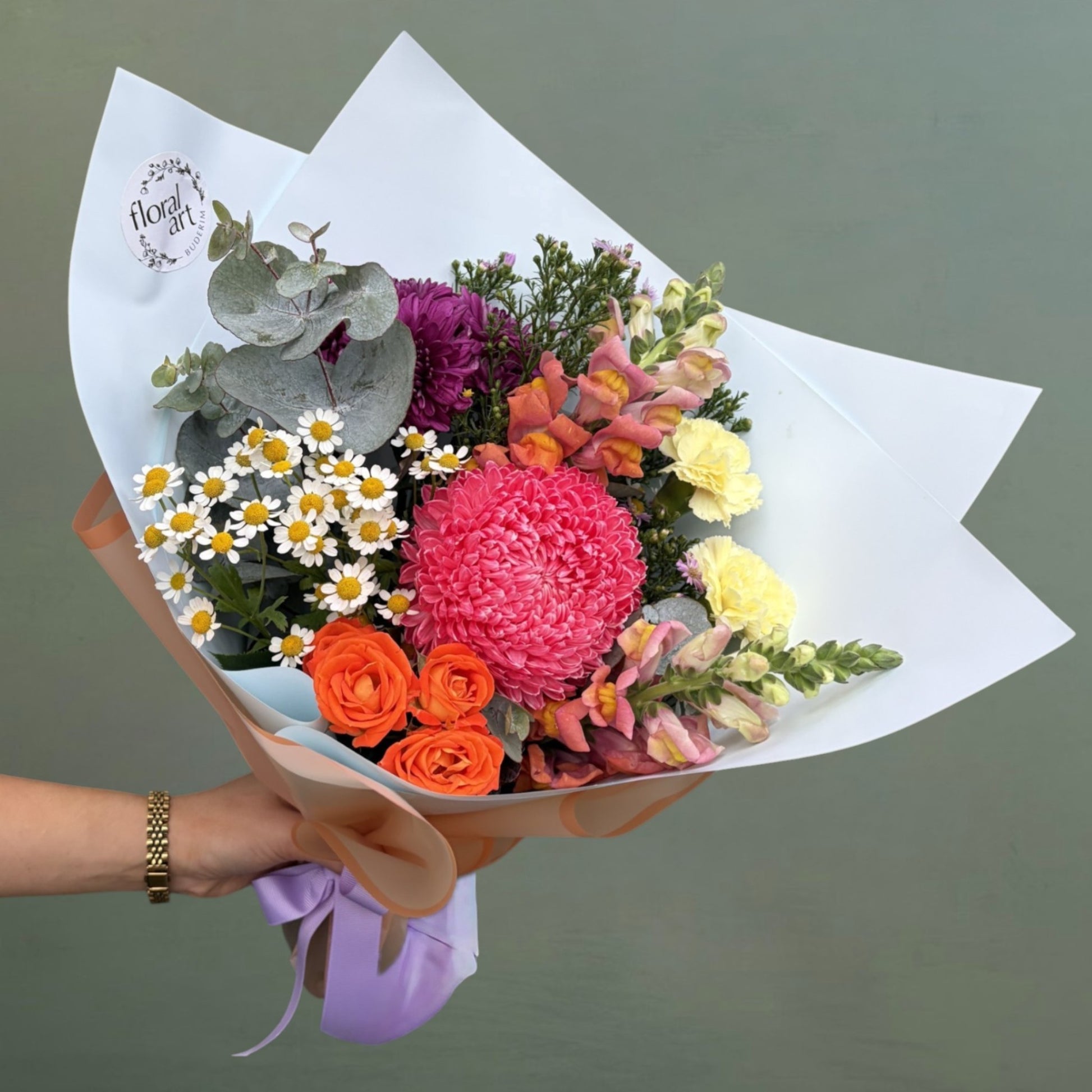 Bouquet of colorful flowers held by a hand with a green background