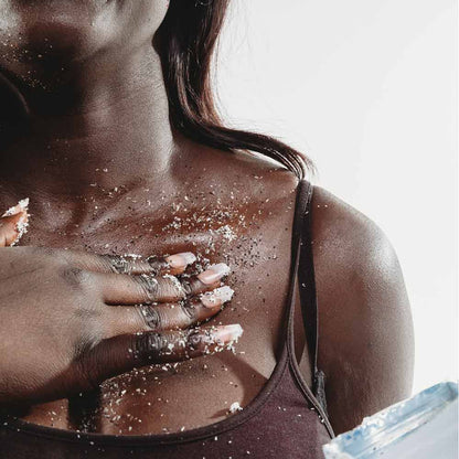 Woman applying scrub product to her skin with a white background