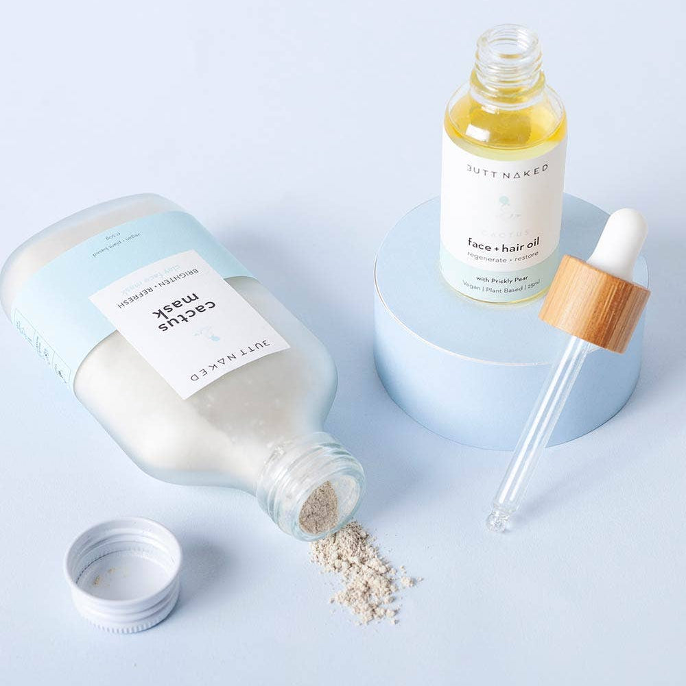 Cosmetic products including a bottle, dropper, and jar on a light blue background