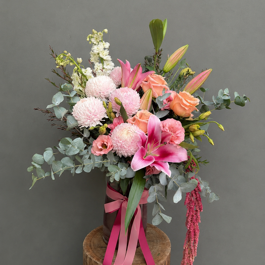 Tall Vase with pink and white flowers on a wooden stand against a green 
background
