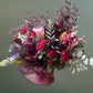burgundy and pink flowers arranged in a  pink ceramic pot 