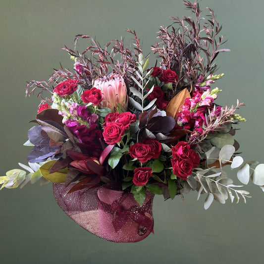 burgundy and pink flowers arranged in a  pink ceramic pot 