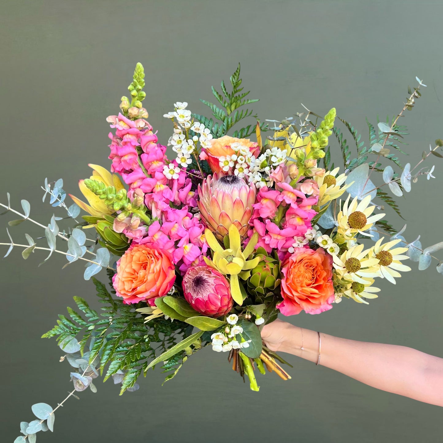 Bouquet of colorful flowers held by a hand against a plain background