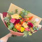 Bouquet of colorful flowers wrapped in brown paper with a green background