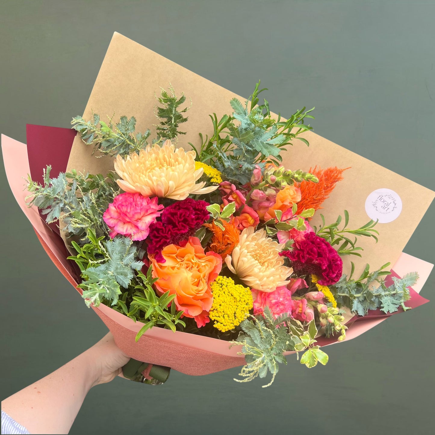 Bouquet of colorful flowers wrapped in brown paper with a green background