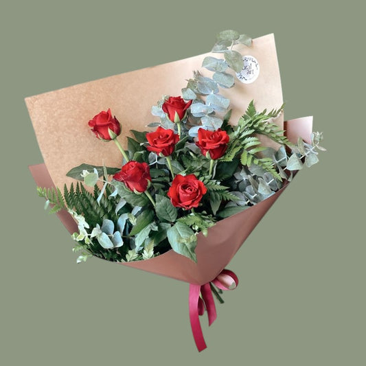 6 red roses wrapped in brown paper