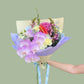Bouquet of luxurious flowers held by a person against a light green background