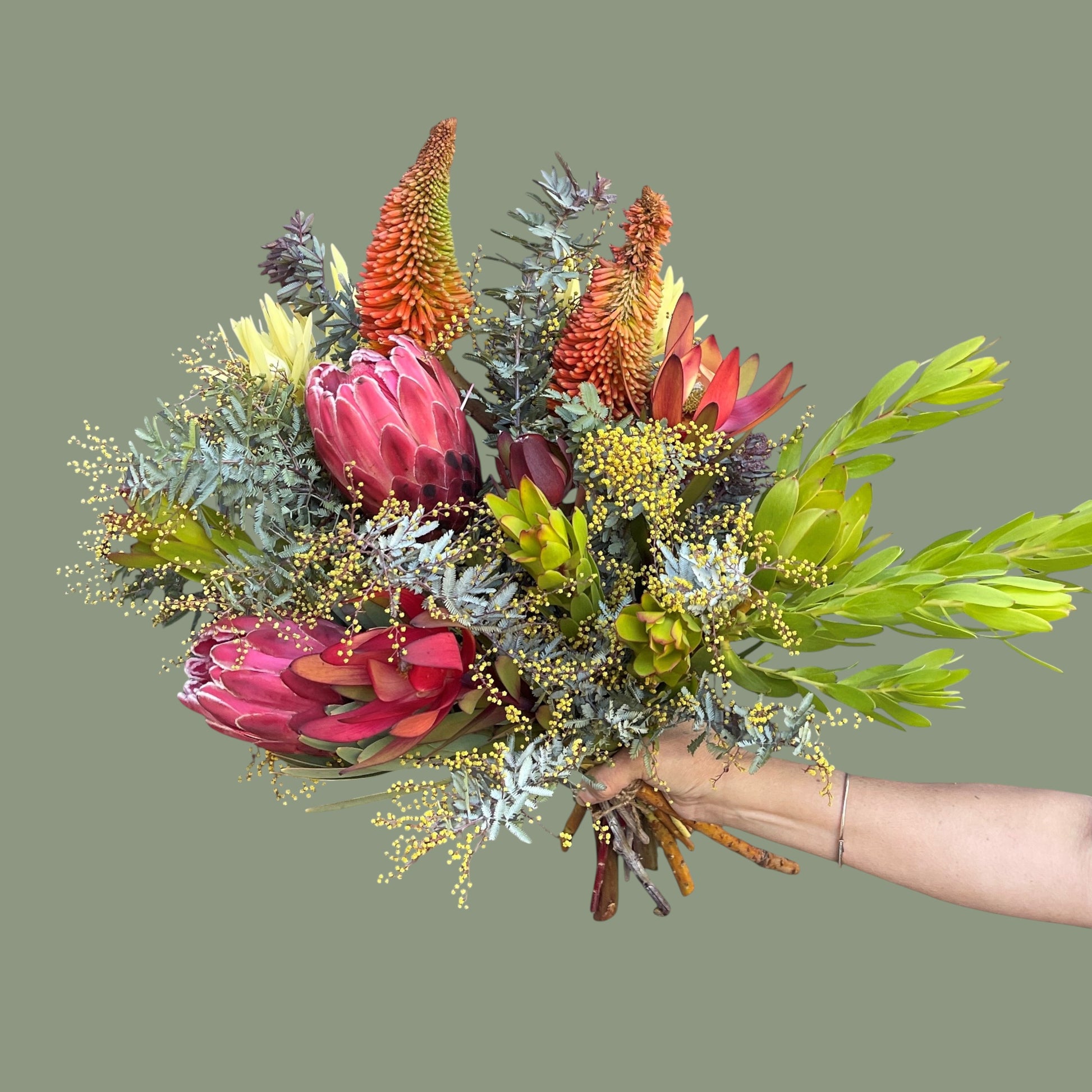 Bouquet of colorful flowers held by a hand on a green background