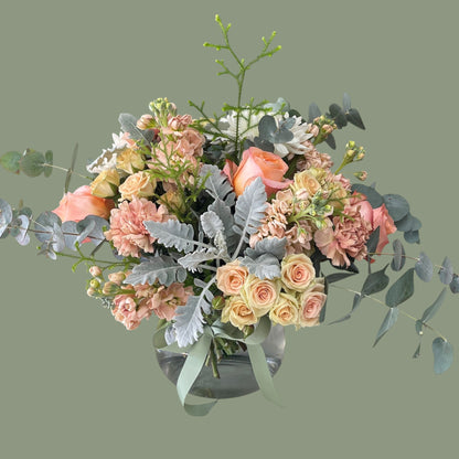 peach and sage flowers arranged in the glass vase