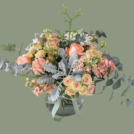 peach and sage flowers arranged in the glass vase