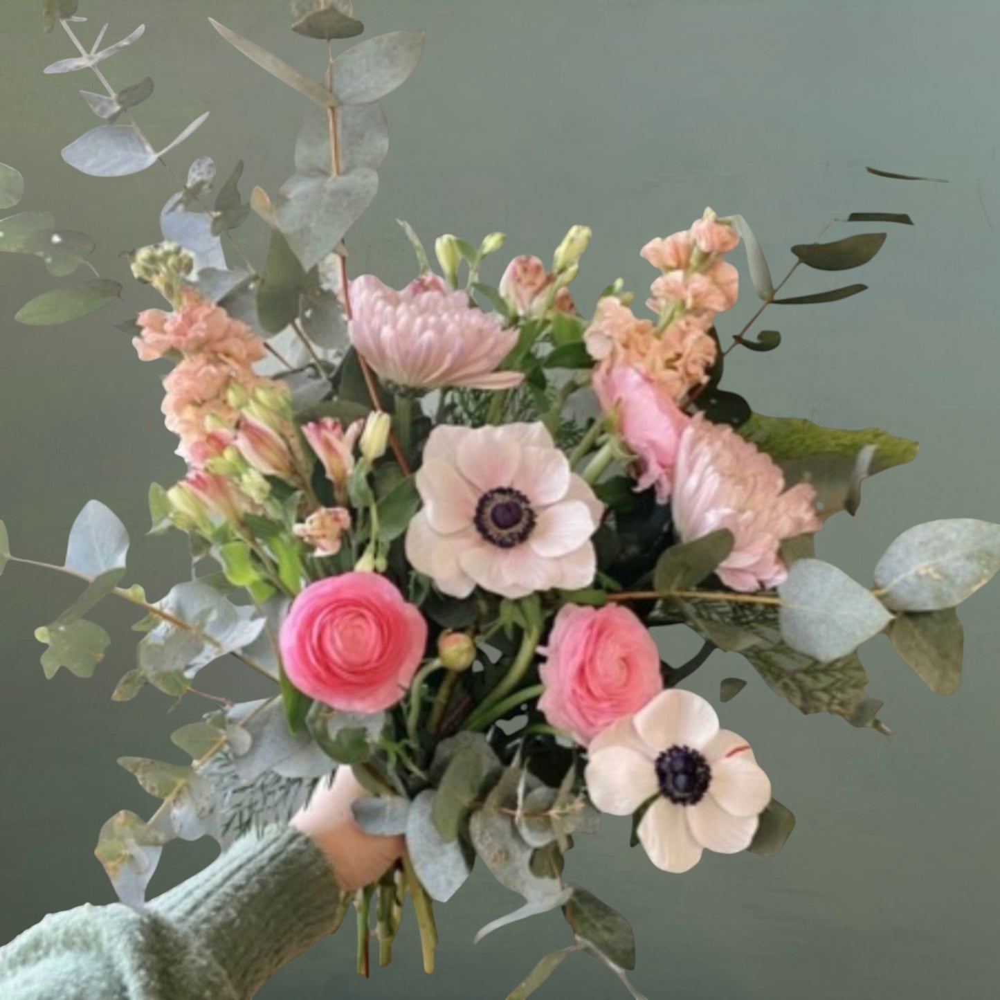 Bouquet of pink and white flowers held by a person against a green background