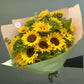 Bouquet of sunflowers wrapped in brown paper with a green bow on a gray background