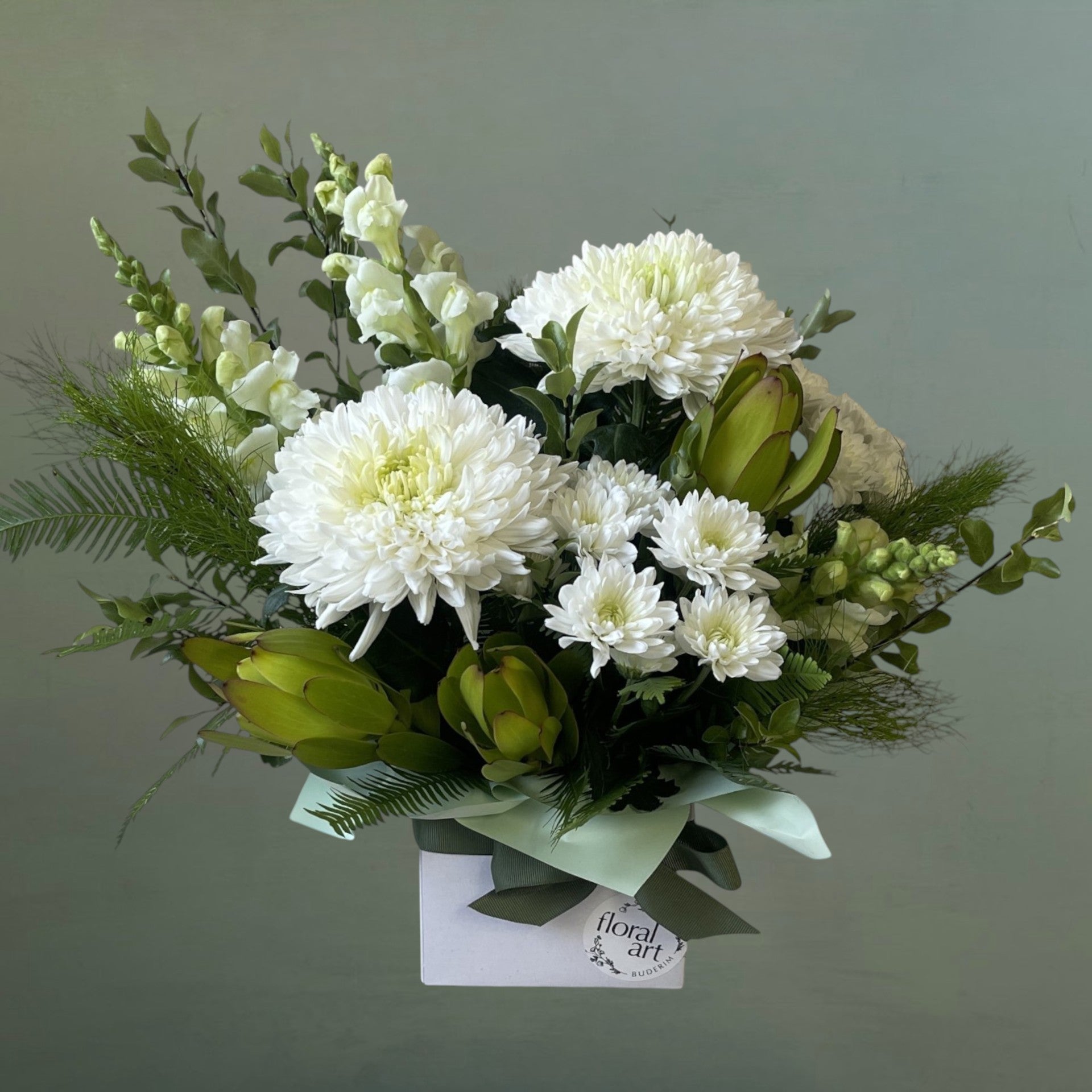 white flowers and greenery in a white box