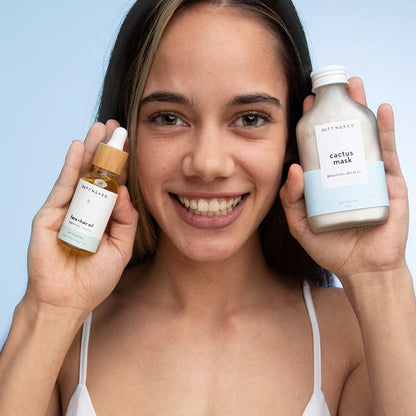 Woman holding two skincare products against a light blue background