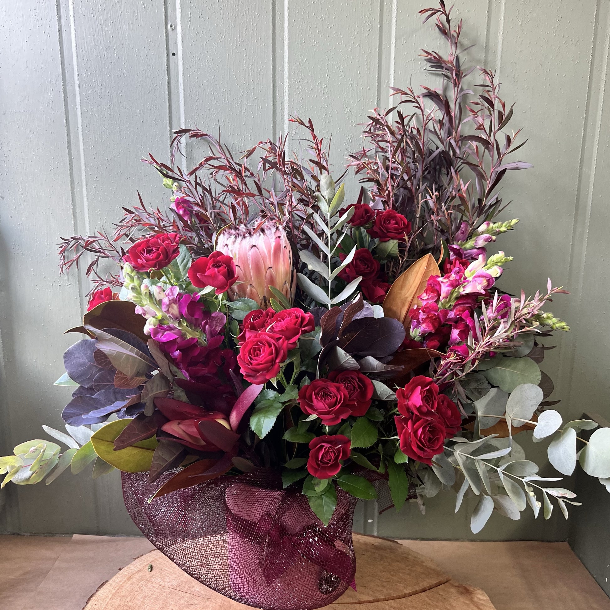 Burgundy toned mixed flowers in ceramic pot