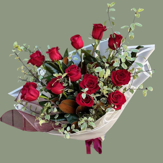 Bouquet of red roses with greenery on a gray background