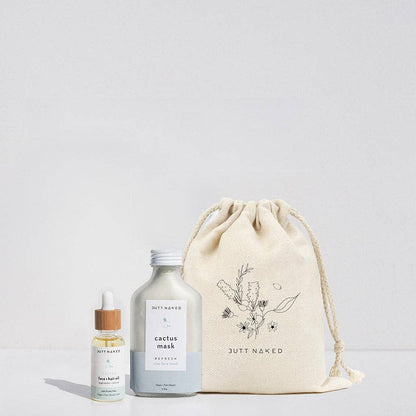 Skincare products including a bottle, dropper, and drawstring bag on a light gray background