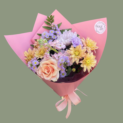 Bouquet of flowers wrapped in pink paper with a visible brand label on a green background