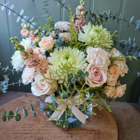 Peach and sage flowers in a fishbowl vase